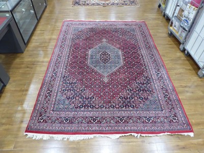 Lot 5 - An Iranian wool carpet with a central pale...