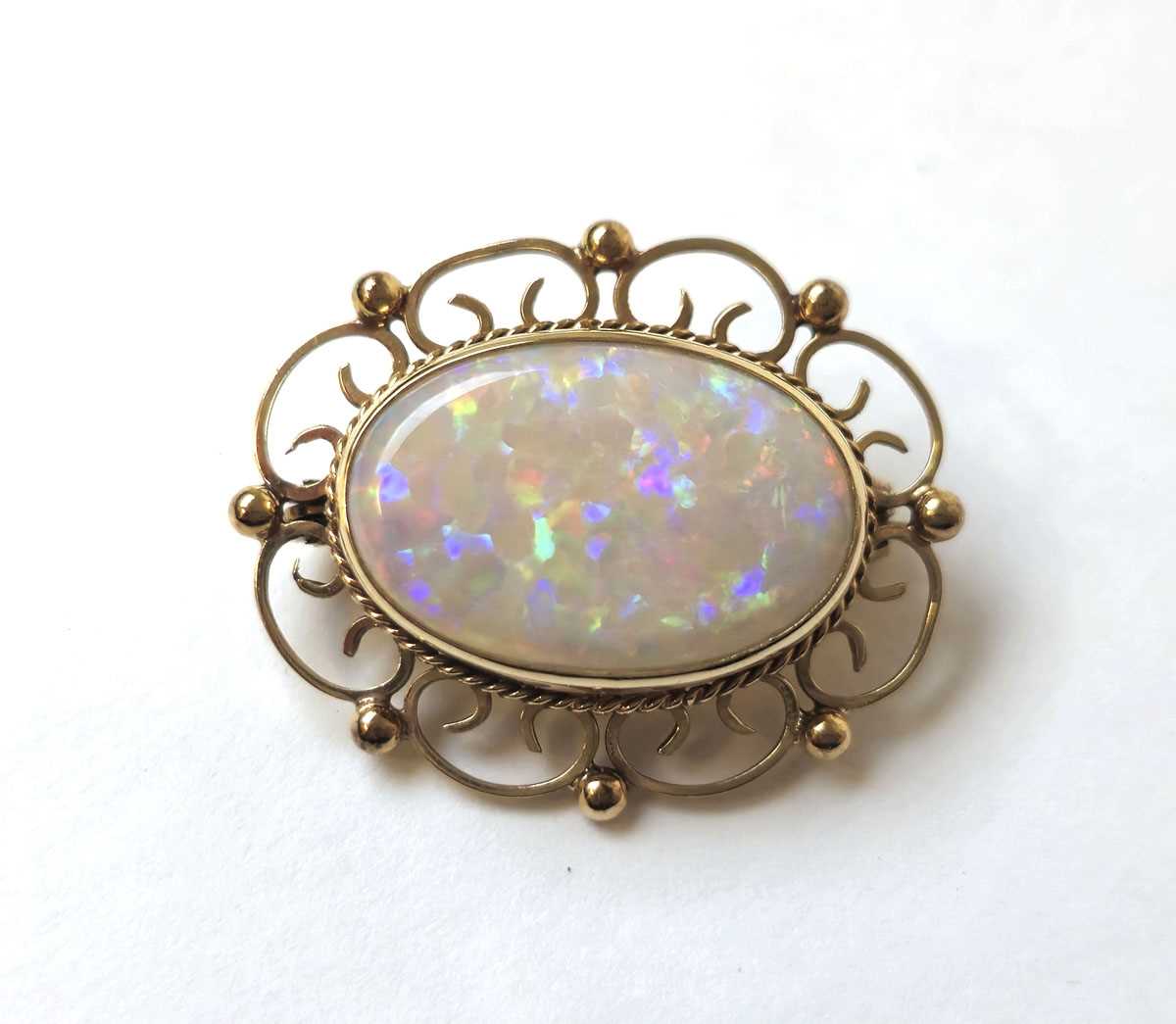 Lot 512 - A 9ct gold and opal brooch with scrolling...