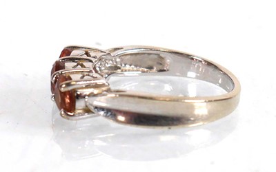 Lot 572 - A 9ct white gold ring set three pale orange...