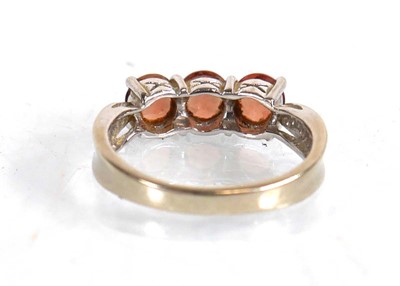 Lot 572 - A 9ct white gold ring set three pale orange...