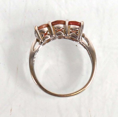 Lot 572 - A 9ct white gold ring set three pale orange...