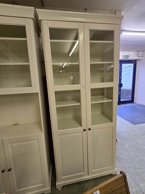 Lot 43 - A modern cream cabinet having a pair of glazed...