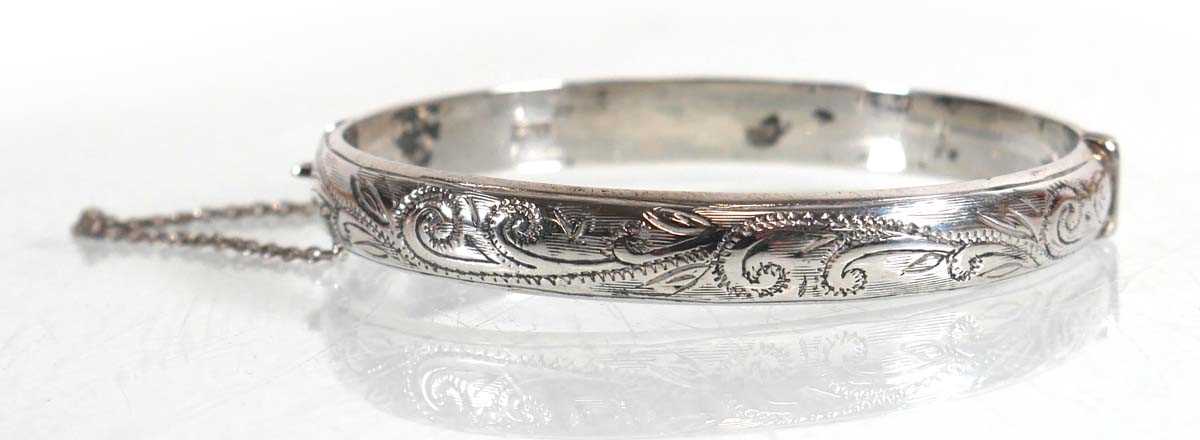 Lot 656 - A silver scroll engraved hinged bracelet,...