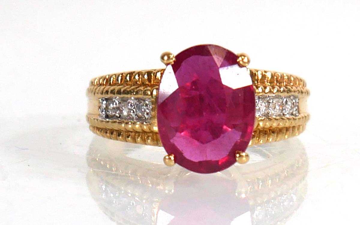 Lot 671 - An 18ct yellow gold ring set oval ruby in a...