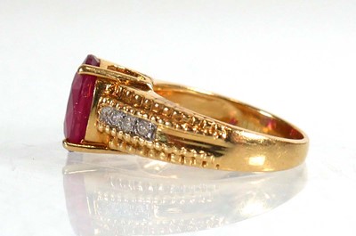 Lot 671 - An 18ct yellow gold ring set oval ruby in a...