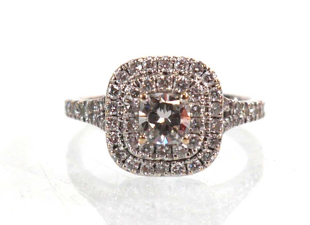 Lot 763 - An 18ct white gold halo ring set centrally...