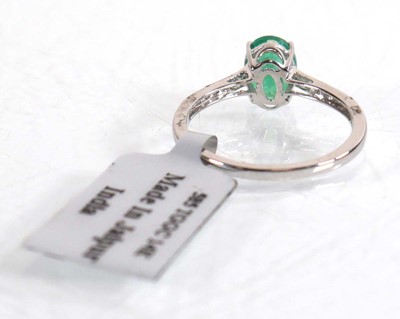 Lot 847 - An 18ct white gold ring set oval emerald in a...