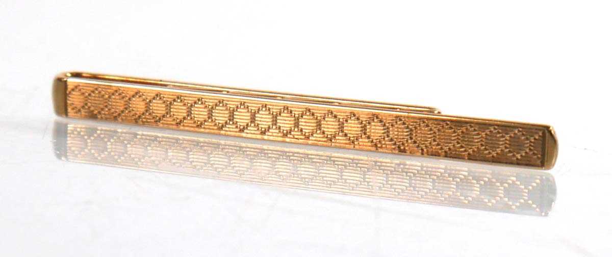 Lot 906 - A 9ct yellow gold engine turned tie clip,...