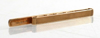 Lot 906 - A 9ct yellow gold engine turned tie clip,...