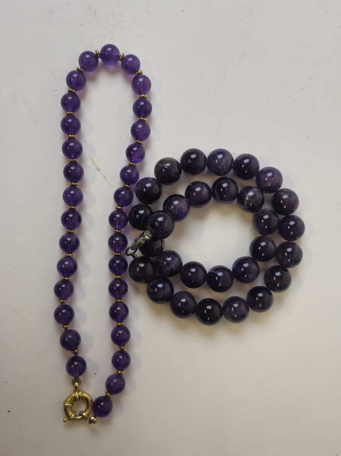 Lot 443 - A string of amethyst beads with a yellow metal...