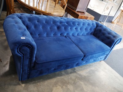 Lot 1057 - Blue velvet sofa upholstered in a chesterfield...