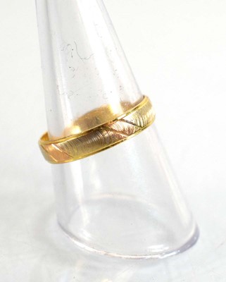 Lot 506 - A tri-colour metal wedding band with engraved...