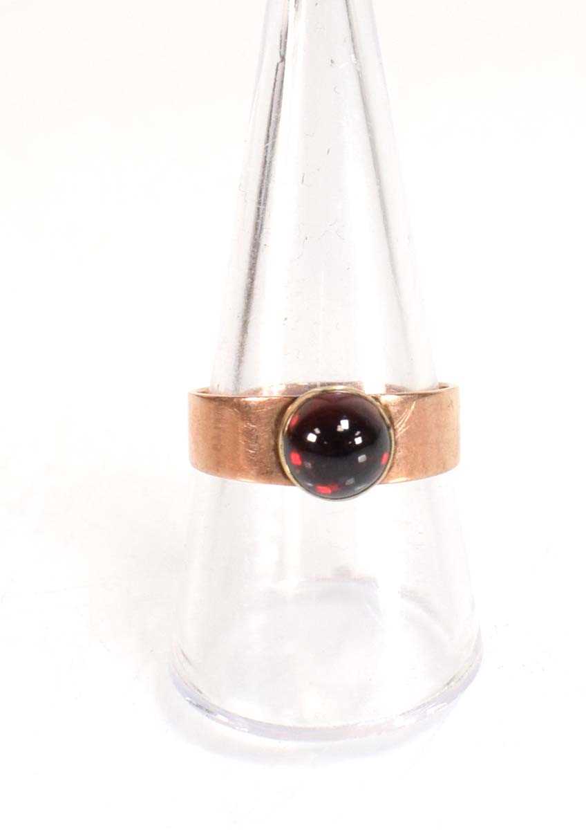 Lot 559 - A yellow metal ring set cabochon red stone in...