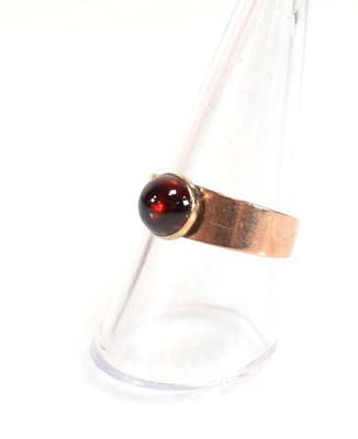 Lot 559 - A yellow metal ring set cabochon red stone in...