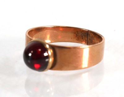 Lot 559 - A yellow metal ring set cabochon red stone in...
