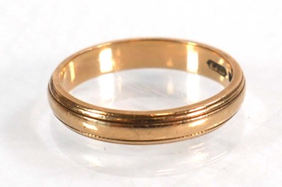 Lot 565 - A 9ct yellow gold wedding band with reeded...