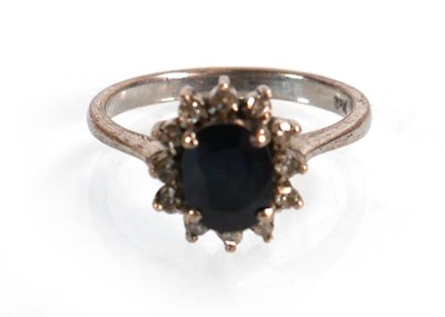 Lot 522 - A white metal ring set oval sapphire within a...