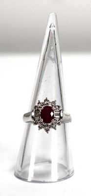 Lot 546 - An 18ct white gold cluster ring set oval ruby...