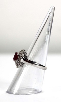 Lot 546 - An 18ct white gold cluster ring set oval ruby...