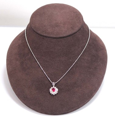 Lot 546 - An 18ct white gold cluster ring set oval ruby...