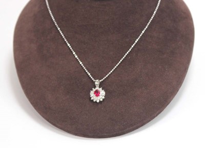 Lot 546 - An 18ct white gold cluster ring set oval ruby...