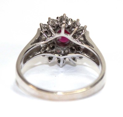 Lot 546 - An 18ct white gold cluster ring set oval ruby...