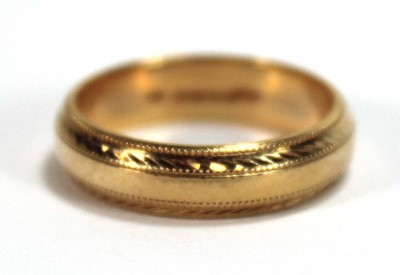 Lot 557 - An 18ct yellow gold wedding band with beaded...