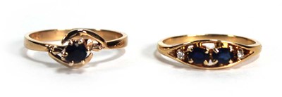 Lot 689 - A yellow metal ring set two small sapphires...