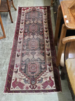 Lot 65 - A distressed cream ground wool runner with...